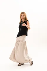 Pollera larga de corte evasé en color arena, con detalle de costura horizontal y frunces en la parte inferior que le otorgan volumen y movimiento.