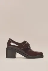 Zapato de cuero vacuno color borgoña con acabado charol, taco cuadrado de 4 cm y hebilla lateral.