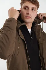 Campera de abrigo estilo parka, color verde militar, con capucha desmontable, cierre frontal con botones y múltiples bolsillos funcionales en pecho, cintura y manga.