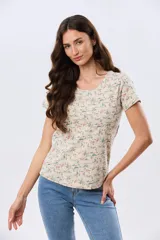 Remera de manga corta con cuello redondo, confeccionada en algodón con estampa de diseño floral en tonos rosados y verdes sobre base beige.