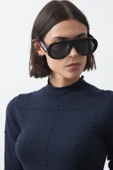 Polera de tejido de punto color celeste, con cuello alto y textura de pequeños puntos en relieve formando una cuadrícula en el frente y las mangas. De corte ajustado y manga larga.
