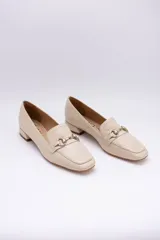 Mocasines de cuero color beige con punta cuadrada y detalle de herraje metálico dorado en el empeine. Cuentan con un taco bajo cuadrado.