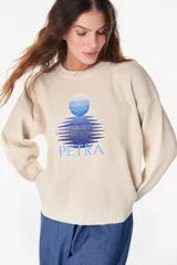 Sweater de punto color amarillo claro, con cuello redondo y diseño holgado. Cuenta con un bordado central en el pecho que representa un sol con su reflejo y la inscripción "PETRA" en tonos naranjas.