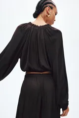 Blusa corta marrón con mangas globo, cuello con volados y escote en V con cordones ajustables.