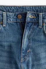 Jean de tiro alto con pierna ancha y corte holgado, confeccionado en denim rígido de cinco bolsillos con cierre y botón.