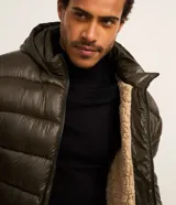 Campera puffer verde militar para hombre, con capucha, cierre frontal, bolsillos con cremallera y forro de sherpa.