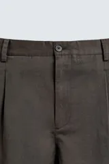 Pantalón de corte relaxed fit confeccionado en tejido de mezcla de algodón y lino. Presenta cintura con pliegues frontales, bolsillos laterales y bolsillos traseros de doble vivo. Cierre frontal con cremallera y botón.