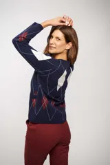 Saco tipo cardigan de punto con diseño de rombos en colores azul, blanco y bordó. Presenta cuello redondo, cierre frontal con botones y bolsillos delanteros.