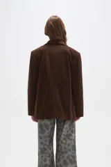 Blazer de pana color marrón, con corte holgado, cuello solapa y cierre frontal con dos botones. Presenta bolsillos laterales con solapa y un bolsillo superior en el pecho.