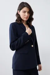 Blazer azul marino de corte clásico, con solapa de muesca, un botón dorado frontal y bolsillos de solapa.