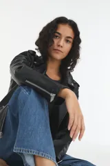 Campera negra de cuero sintético, estilo biker, con cierre cruzado y múltiples bolsillos con cremallera.
