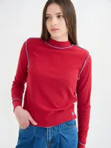 Polera básica de algodón en tejido rib, color turquesa, de manga larga, con hombreras y detalles de pespuntes en color contrastante en las terminaciones y el cuello.