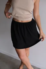 Pollera corta negra de jersey con cintura elástica y diseño liso.