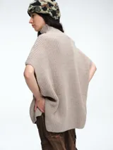 Chaleco tipo poncho de tejido de punto color tostado, con cuello polera y diseño holgado con laterales abiertos.