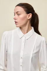 Camisa de manga larga color celeste, con cuello clásico y botonadura frontal. Presenta un calce relajado, con mangas amplias y puños anchos.