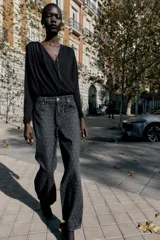 Jeans de tiro alto, corte recto y largo, color negro lavado, con abalorios brillantes distribuidos por toda la prenda.