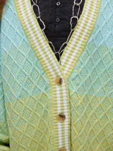 Cardigan de punto con diseño degradé en tonos tierra, patrón de rombos en relieve, cuello en V con cartera de botones y puños con rayas blancas y marrones.