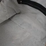 Bolso de mano tipo duffle de cuero negro, con doble asa corta y correa larga regulable con el logo de la marca. Tiene cierre superior y dos bolsillos frontales con cierre.
