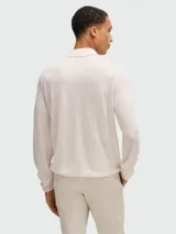 Polo de punto color crema, de corte slim-fit, manga larga y cuello polo con tres botones.