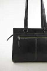 Cartera de cuero marrón de tamaño medio con diseño estructurado, que combina cuero liso y un panel frontal texturizado tipo cocodrilo con bolsillo exterior con cierre. Cuenta con doble asa de hombro y costuras visibles de contraste.