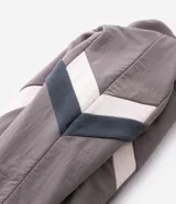 Buzo de fleece con cierre frontal completo y cuello alto. Presenta un diseño con recortes en tonos blanco y negro en las mangas y laterales, y cuenta con una estampa pequeña en el pecho.
