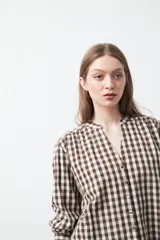 Camisa de algodón con estampado de cuadros vichy en tonos azul y blanco. Presenta escote en V con cierre frontal de botones, mangas largas con puños y un corte levemente holgado con frunces en hombros y espalda.