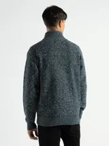 Campera de punto con cierre frontal, cuello alto y forro interno. Presenta un diseño de tejido jaspeado con puños y ruedo acanalados, e incluye un pequeño aplique de marca en la parte inferior.