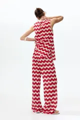 Pantalón tejido en punto jacquard estilo crochet, con diseño de rayas en zigzag de colores rojo y blanco, de tiro medio y piernas amplias.