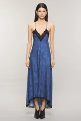 Vestido maxi azul de satén con diseño levemente asimétrico, corte al bies y escote en V con detalle de puntilla negra. Presenta espalda deportiva con tirantes finos regulables y ribete de encaje en el ruedo.