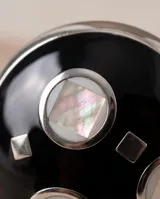Anillo de acero de diseño redondo, con esmalte negro y detalles en nácar.