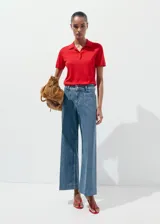 Jeans wide leg de tiro alto en tejido denim azul, con bolsillos de parche delanteros, trabillas para cinto y cierre frontal con cremallera y botón.