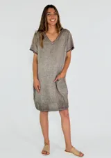 Vestido corto color beige, corte recto, con cuello en V y mangas cortas. Presenta un bolsillo de parche en el frente.