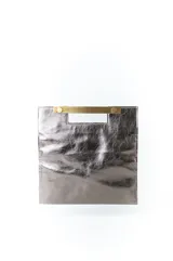 Cartera de mano tipo sobre color plateado, con textura arrugada y asa metálica dorada. Cierre con broche imantado.