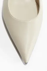 Zapato de vestir destalonado color crema, con punta fina, taco kitten y tira elástica lateral en el talón.