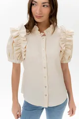 Camisa celeste de lino con cuello mao y mangas cortas abullonadas con volados. Cierre frontal con botones.