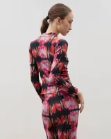 Polera de manga larga con cuello alto, confeccionada en tela sublimada con estampado abstracto en tonos rojizos, rosados y negros.
