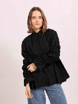 Camisa de lino color negro, con cuello mao, cierre frontal oculto y mangas largas fruncidas con puños amplios.