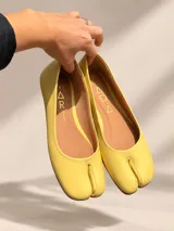 Zapatos tipo ballerinas de diseño Tabi, color amarillo, con punta dividida característica y suela plana.