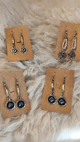 Caravanas colgantes de metal plateado con detalles de tiento trenzado y dijes circulares con grabados tradicionales.