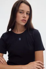 Camiseta de rib color negro, con cuello redondo y manga corta. Presenta un pequeño bordado en el centro del pecho.