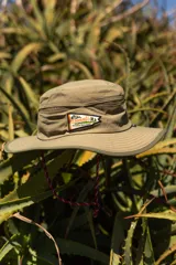 Sombrero tipo pescador color beige con ala ancha, borde reforzado, correa ajustable y parche frontal con el logo de Denali.