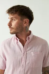 Camisa de manga corta confeccionada en una mezcla de lino y algodón, con cuello camisero, cierre frontal de botones y bolsillo en el pecho con logo bordado.