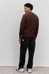 Sweater de tejido de punto acanalado en color marrón, con cuello redondo y ajuste holgado. Presenta un pequeño bordado distintivo en el pecho.