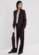 Blazer de lino color bordó con diseño recto, cuello pico con solapa, mangas largas y cierre de doble botonadura.