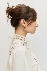 Camisa de manga larga abullonada color marrón, con detalles de bordados calados en el pecho y las mangas, y cierre frontal con botones.