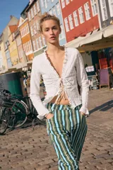 Top de manga larga con textura nido de abeja, escote en pico con detalle de volantes y cierre frontal mediante lazos ajustables.