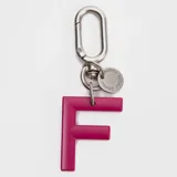 Llavero o charm de letra A en color fucsia, con mosquetón metálico y dije circular pequeño con la marca grabada.