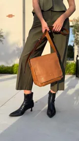 Bandolera de diseño simple con tapa frontal, confeccionada en material símil cuero. Cuenta con correa ajustable, división interna y bolsillos internos para mayor organización.