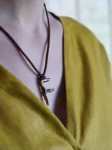 Collar de tiento de cuero marrón con dije en forma de letra y placa metálica con la inscripción de la marca.