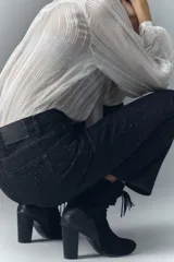 Jean de tiro alto, color negro, con corte acampanado y pequeños apliques brillantes distribuidos por toda la tela.